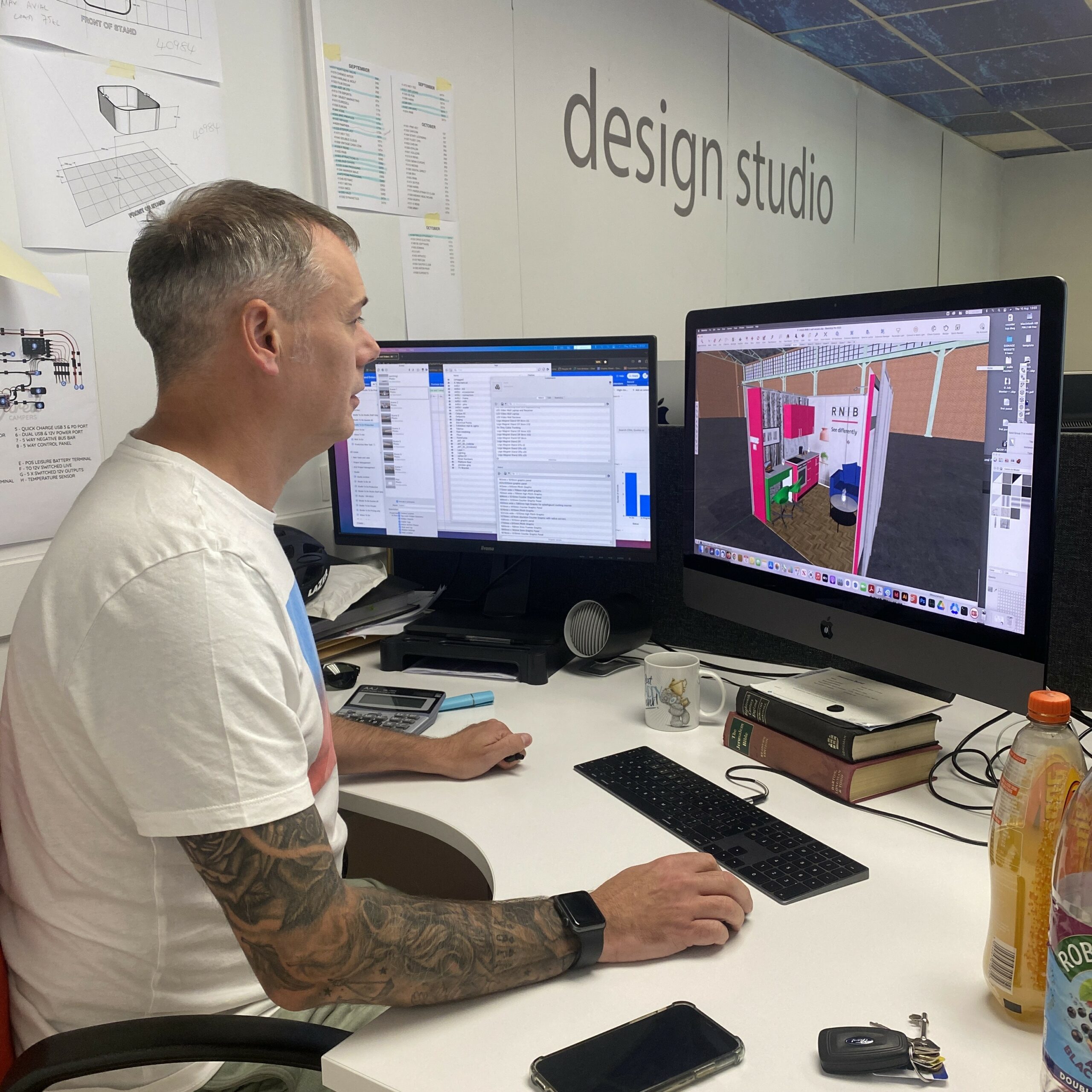 designer-working-at-a-desk-in-a-design-studio-viewing-a-3D-exhibition-stand-render